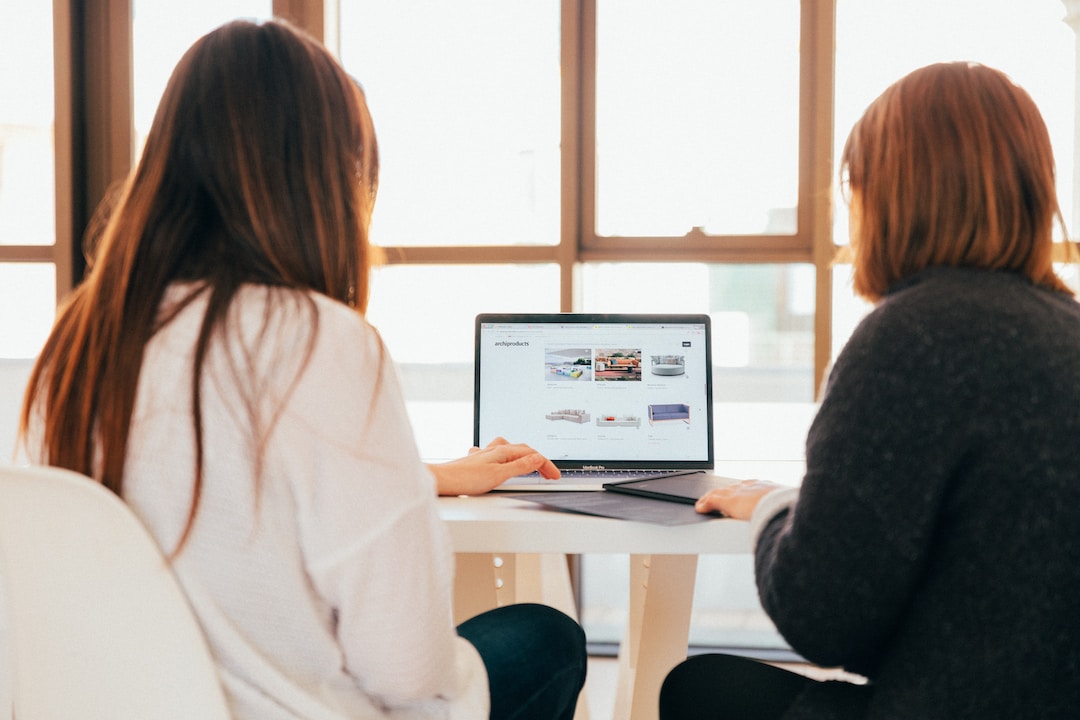 Alt Text: Two women at a table, typing on a laptop.